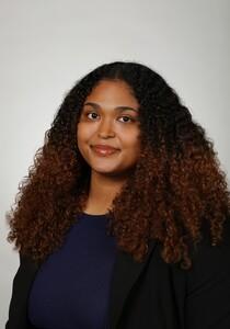 Studio portrait photograph of smiling woman with long curly brown ombré hair