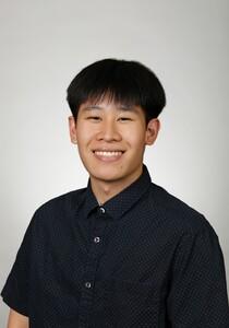 Smiling young person in dark button shirt, neutral gray background, portrait